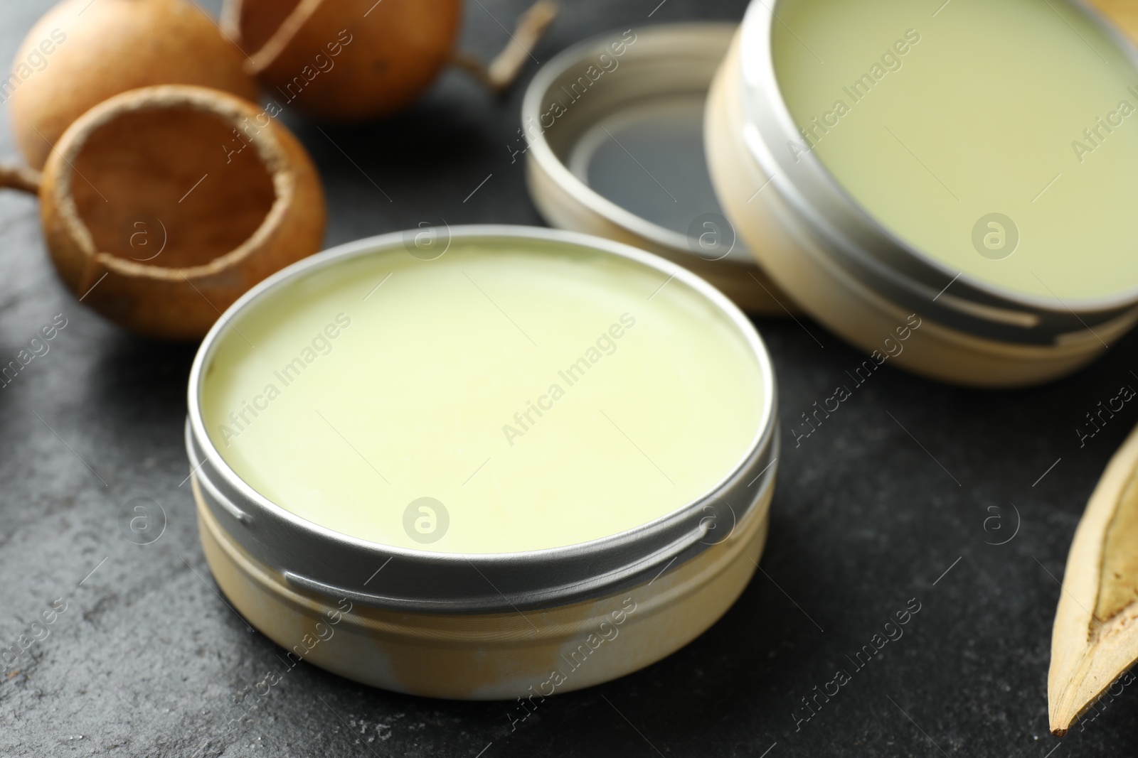 Photo of Natural solid perfume and dry fruit peels on black table, closeup