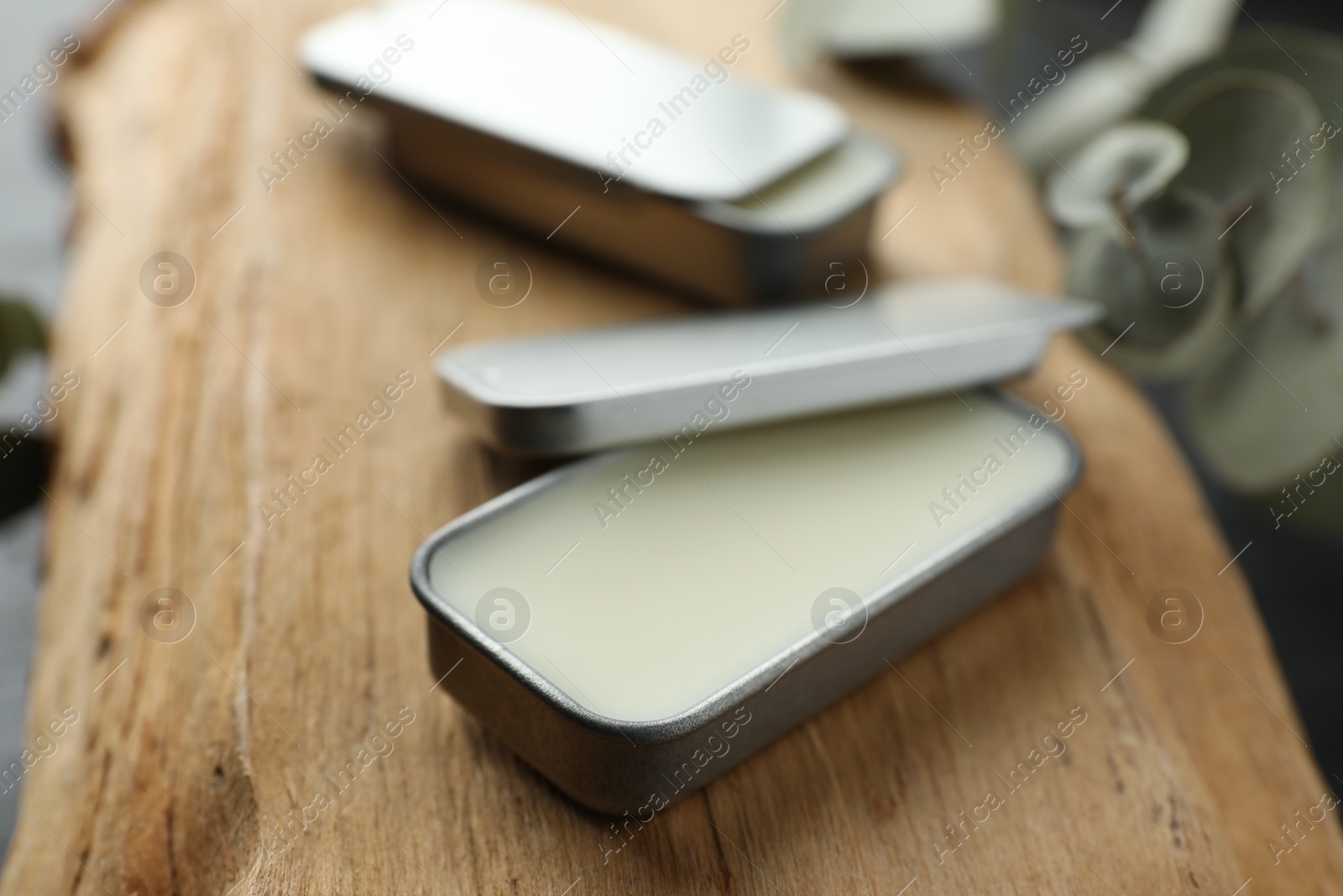 Photo of Natural solid perfume in containers on wood, selective focus