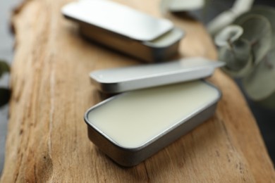 Photo of Natural solid perfume in containers on wood, selective focus