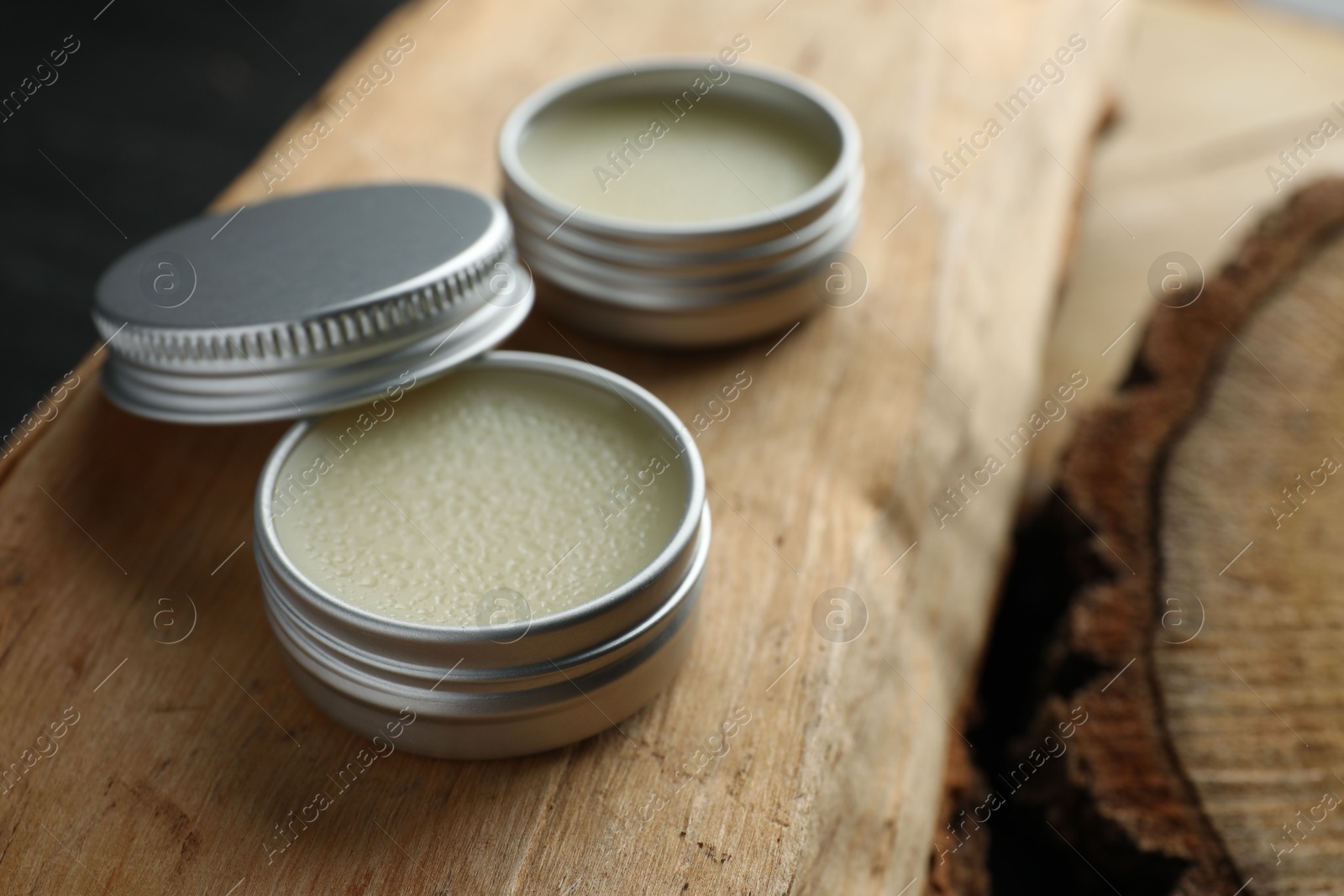 Photo of Natural solid perfume in containers on wood, selective focus