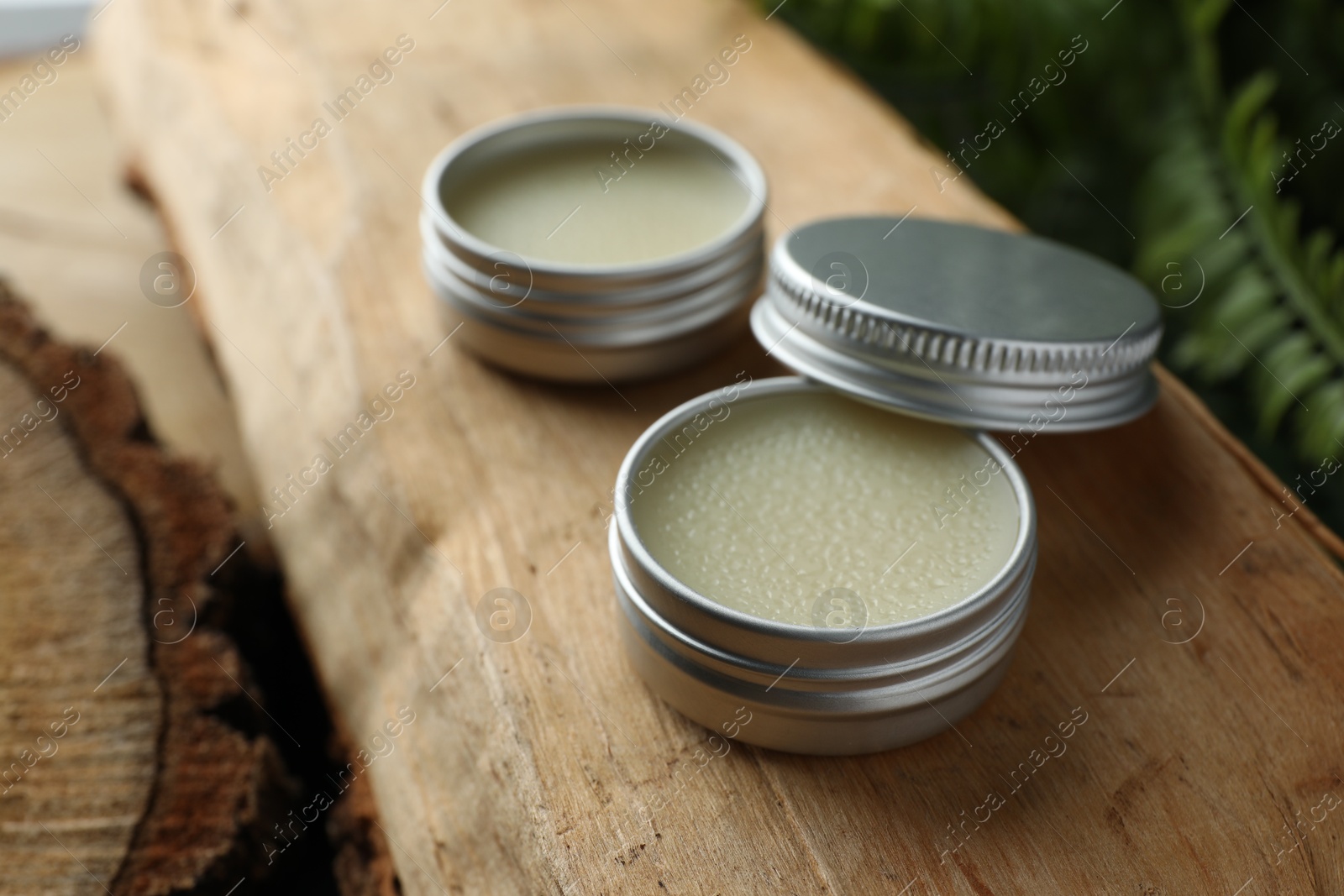 Photo of Natural solid perfume and plant on wood, closeup