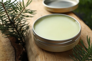 Photo of Natural solid perfume and fir twigs on wood, closeup