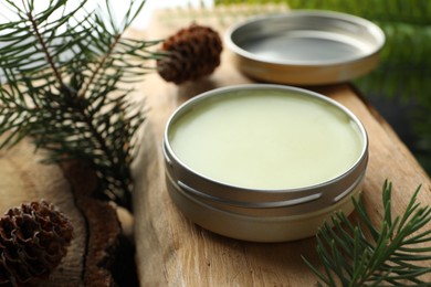 Photo of Natural solid perfume and fir twigs on wood, closeup