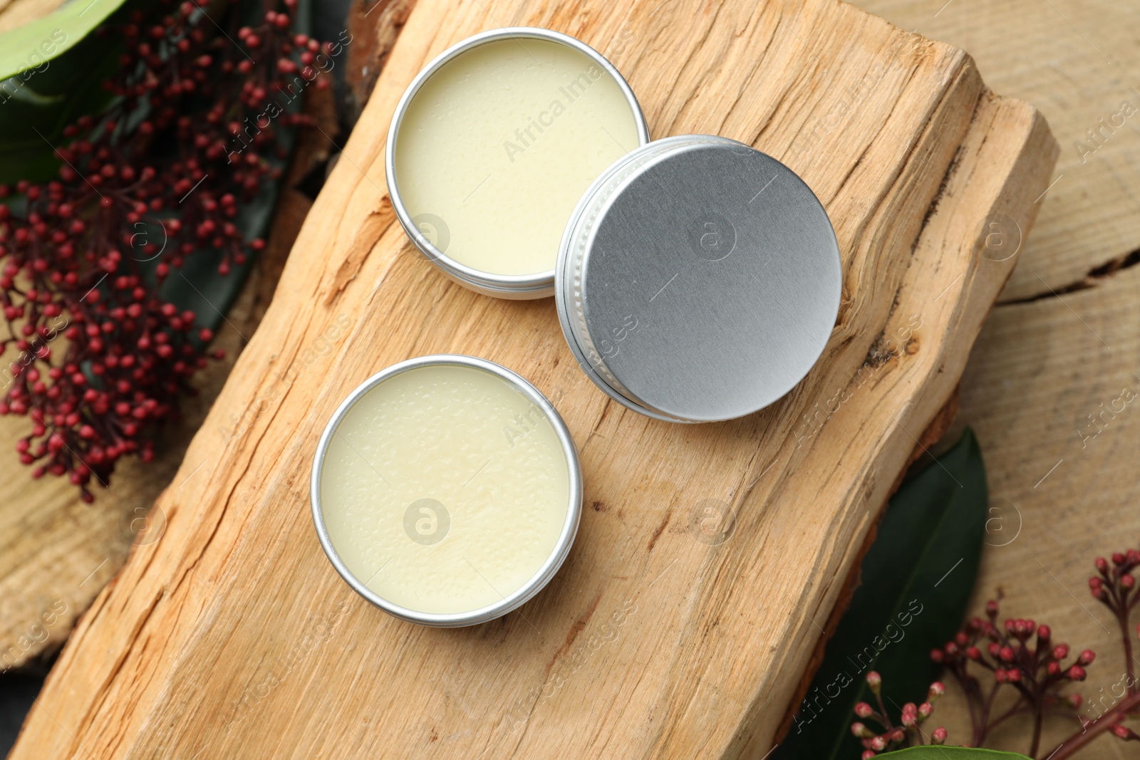 Photo of Natural solid perfume and skimmia plant on wood, top view