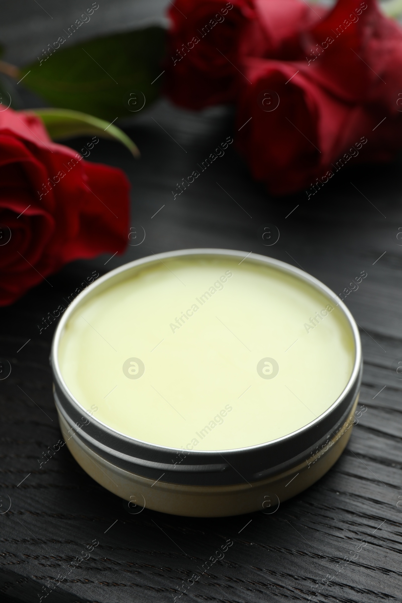 Photo of Natural solid perfume and roses on black wooden table, closeup