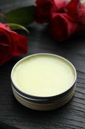 Photo of Natural solid perfume and roses on black wooden table, closeup