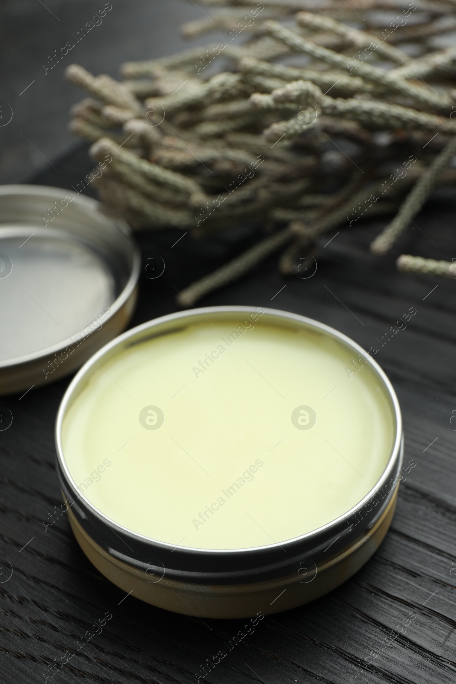 Photo of Natural solid perfume and plant on black wooden table, closeup