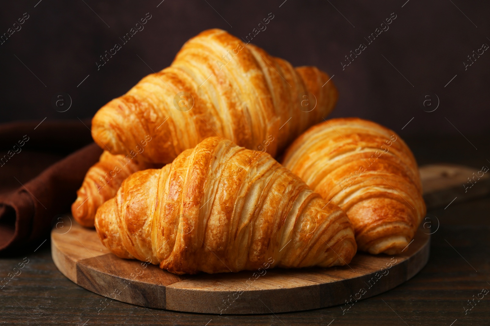 Photo of Tasty fresh croissants on wooden table, closeup. Puff pastry