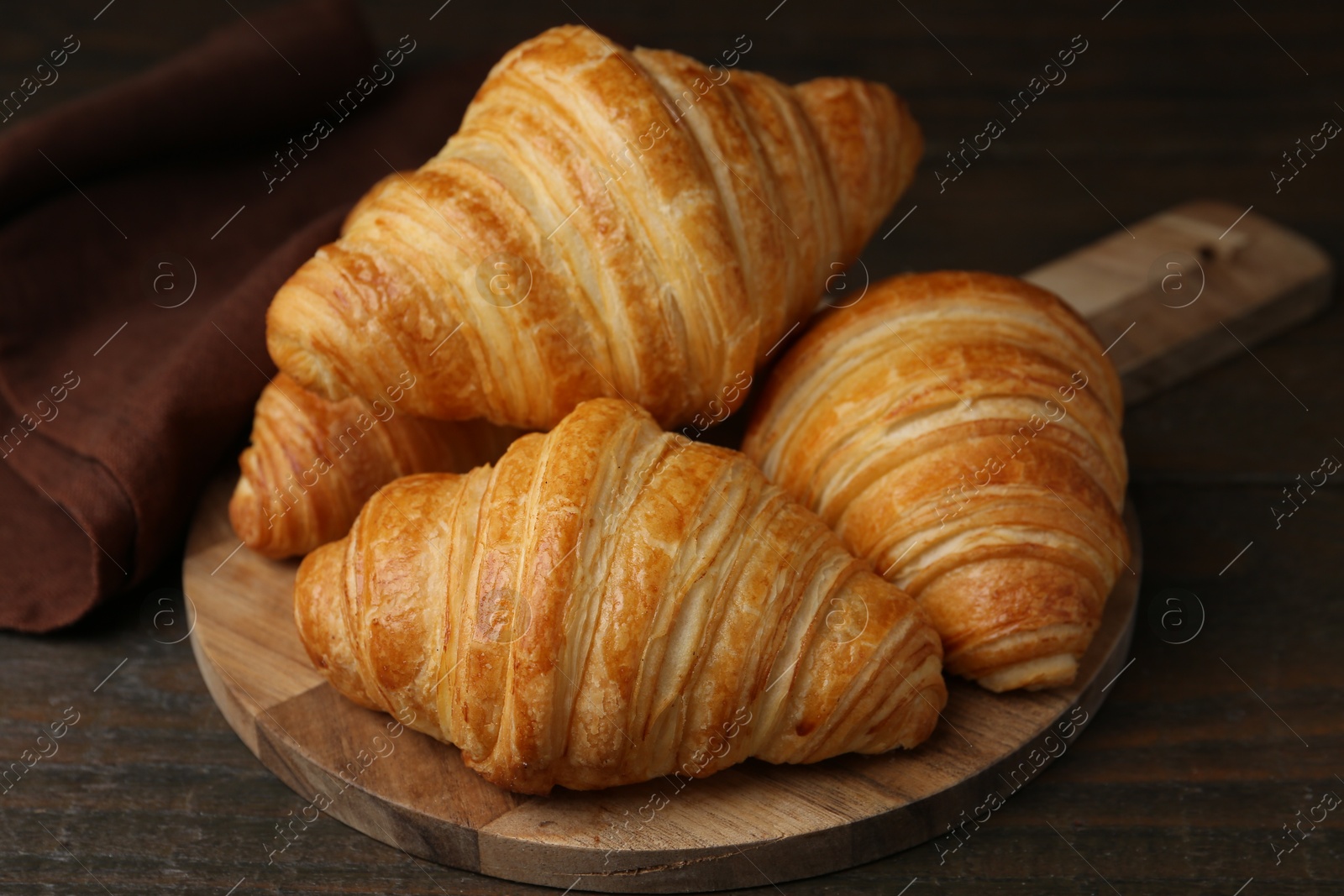 Photo of Tasty fresh croissants on wooden table, closeup. Puff pastry