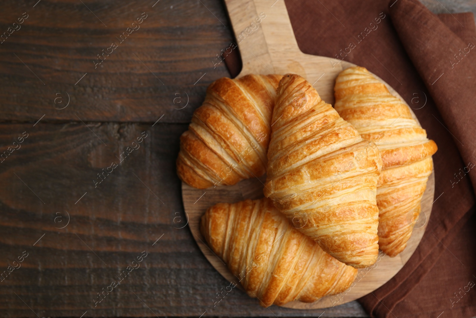 Photo of Tasty fresh croissants on wooden table, top view. Space for text