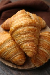 Photo of Tasty fresh croissants on wooden table, closeup. Puff pastry