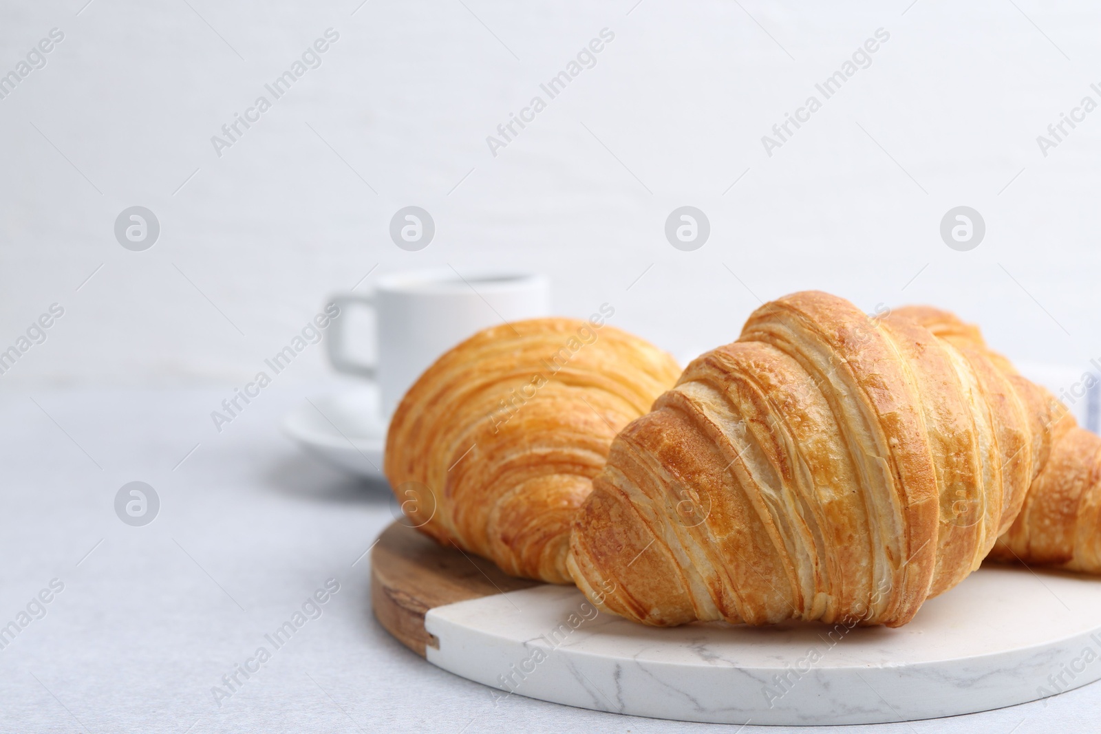 Photo of Tasty fresh croissants on light table, closeup. Space for text