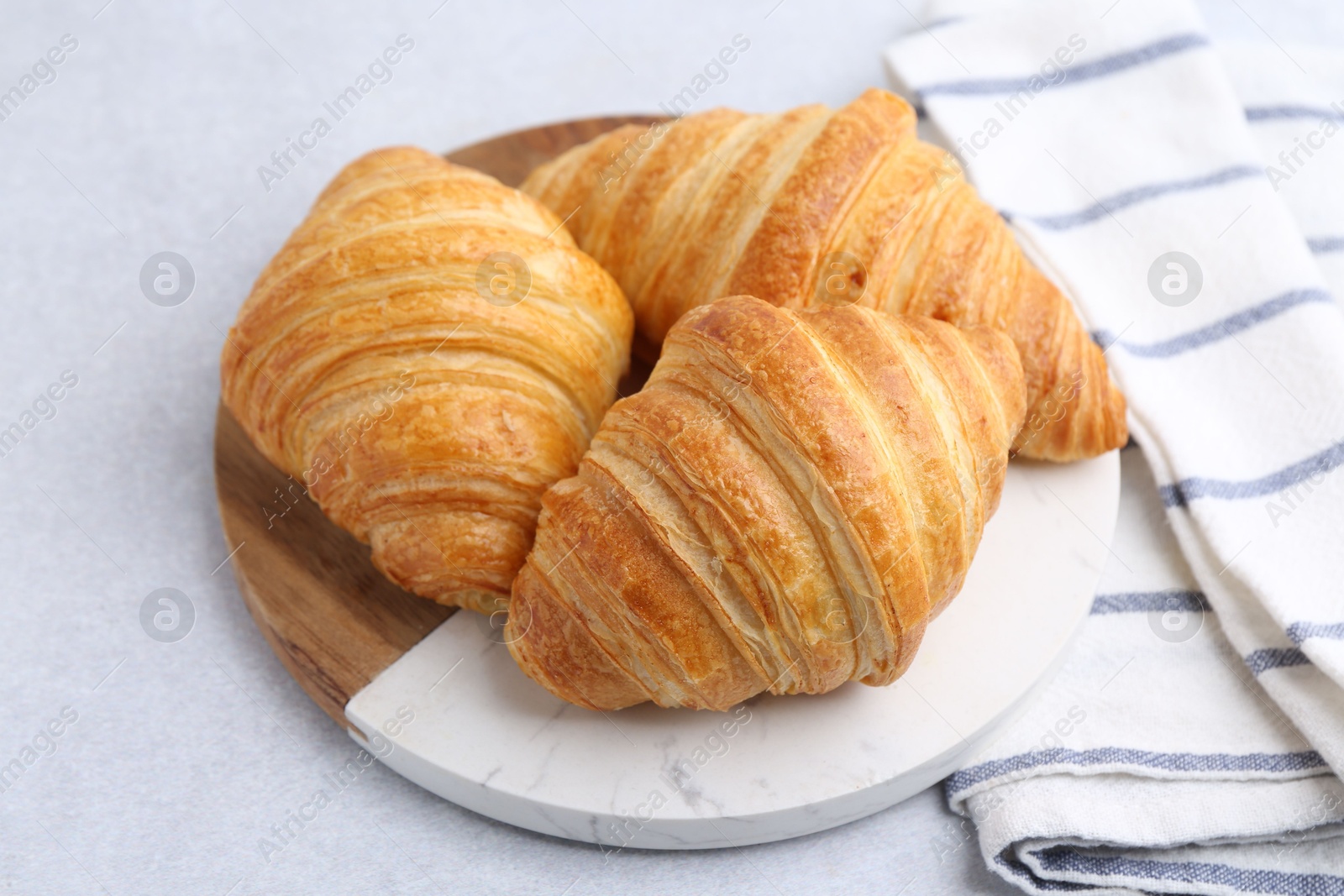 Photo of Tasty fresh croissants on light grey table, closeup