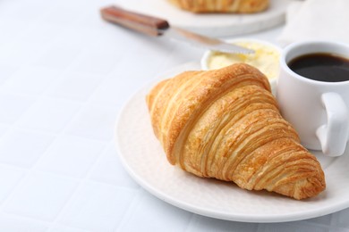 Photo of Tasty fresh croissant served with butter and cup of coffee on white tiled table, closeup. Space for text