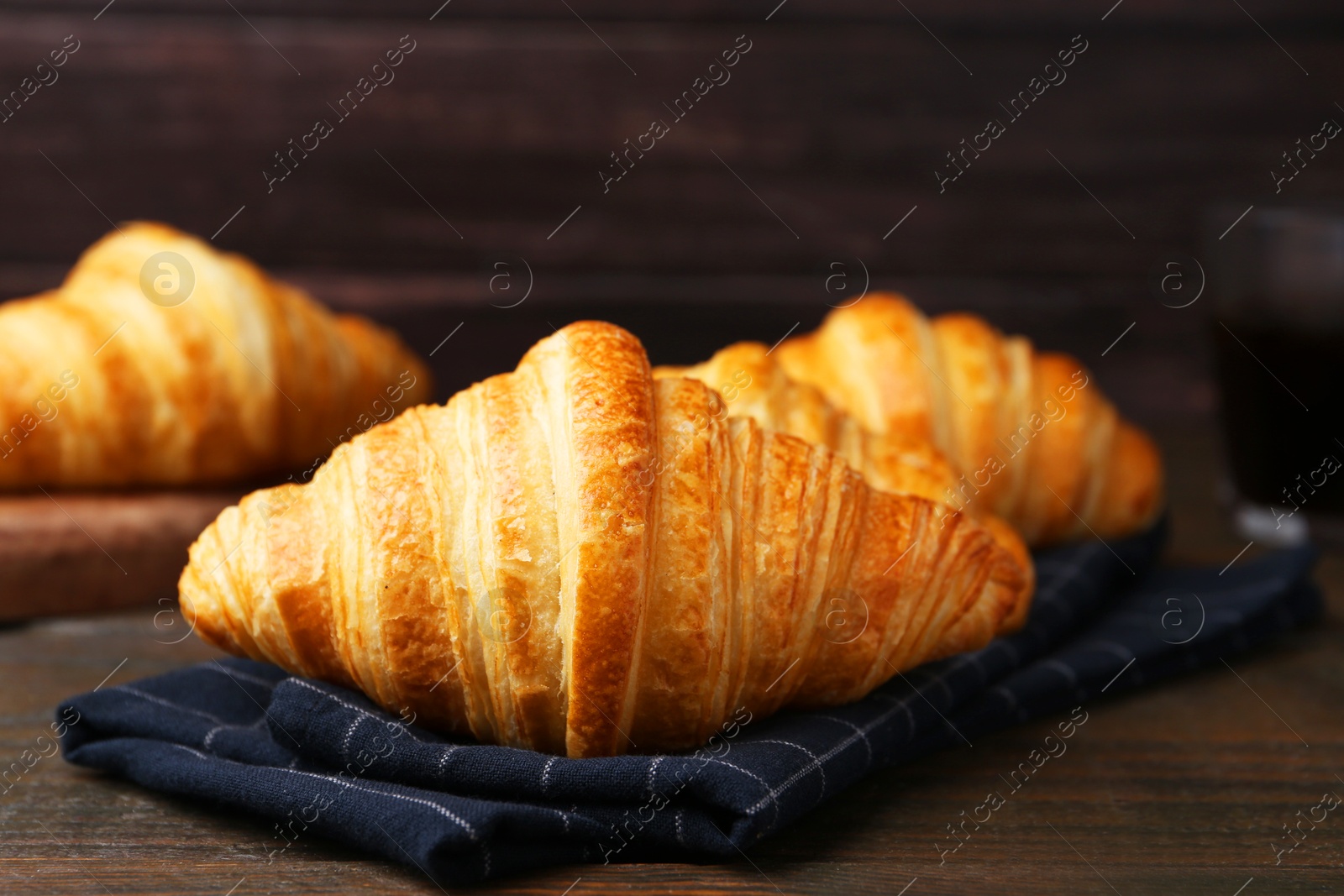 Photo of Tasty fresh croissants on wooden table, closeup. Puff pastry