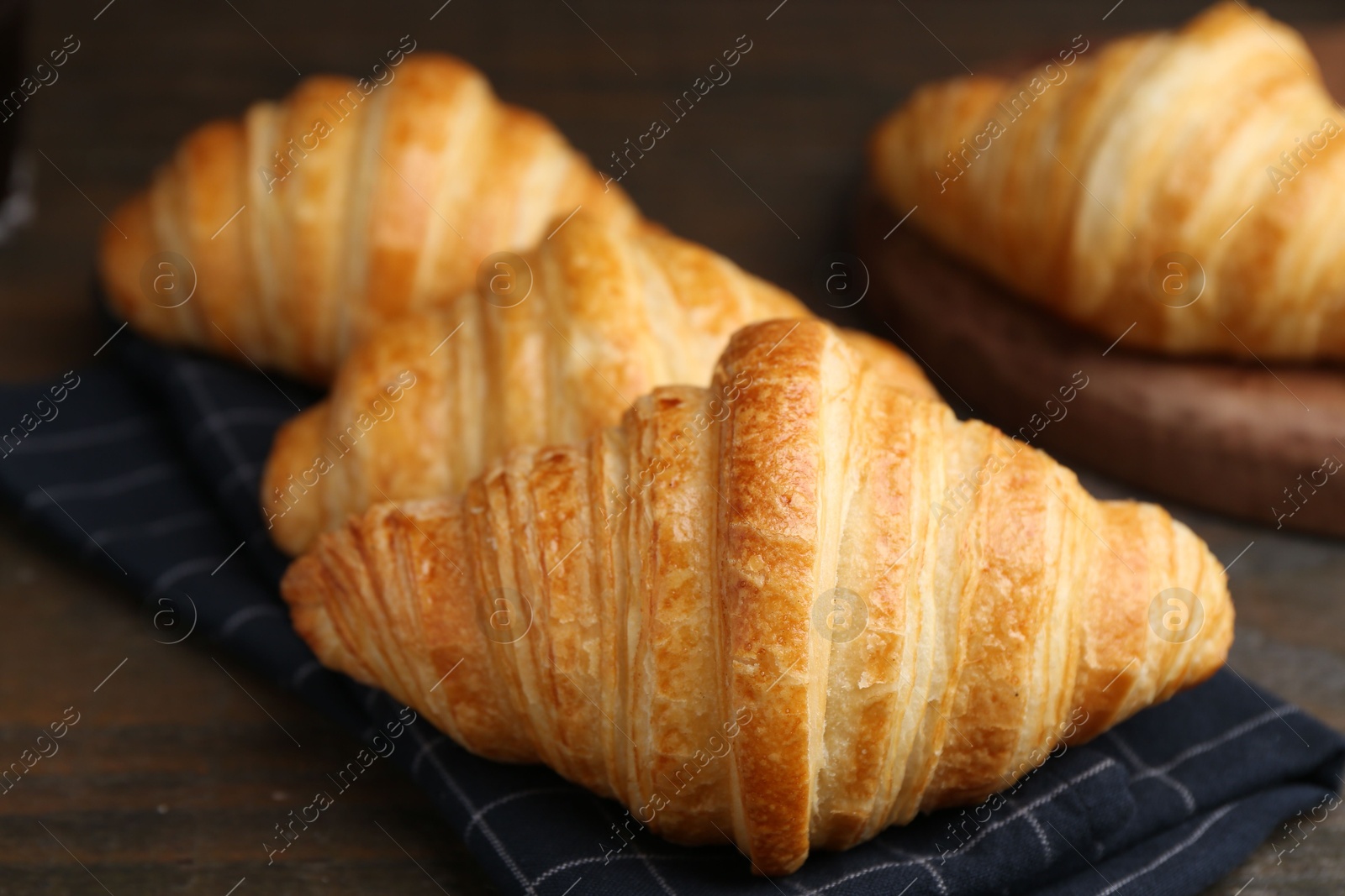 Photo of Tasty fresh croissants on wooden table, closeup. Puff pastry