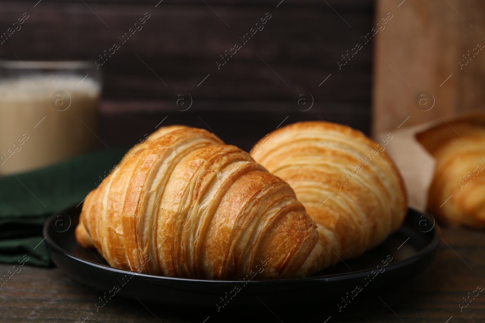 Photo of Tasty fresh croissants on wooden table, closeup. Puff pastry