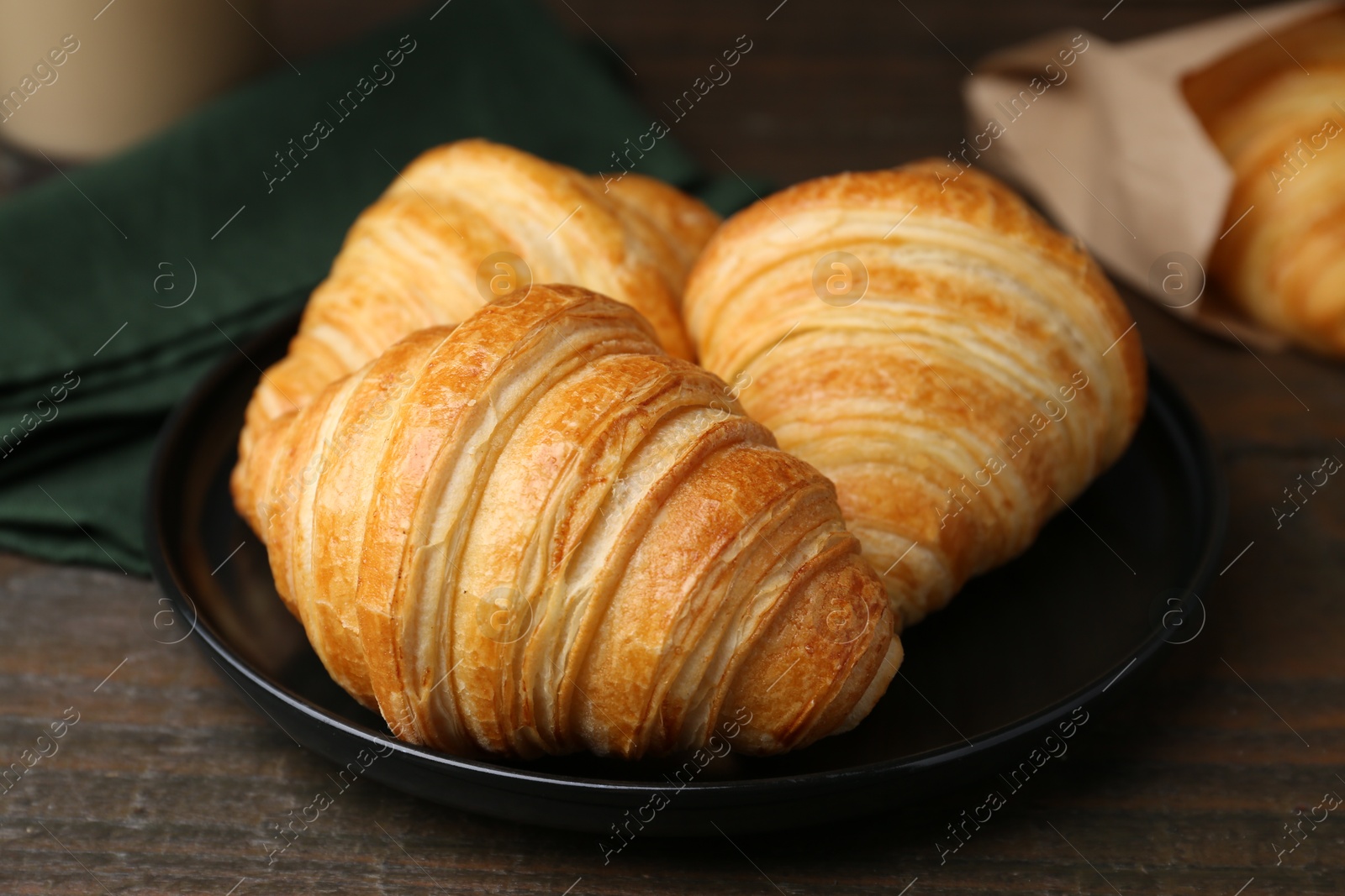 Photo of Tasty fresh croissants on wooden table, closeup. Puff pastry