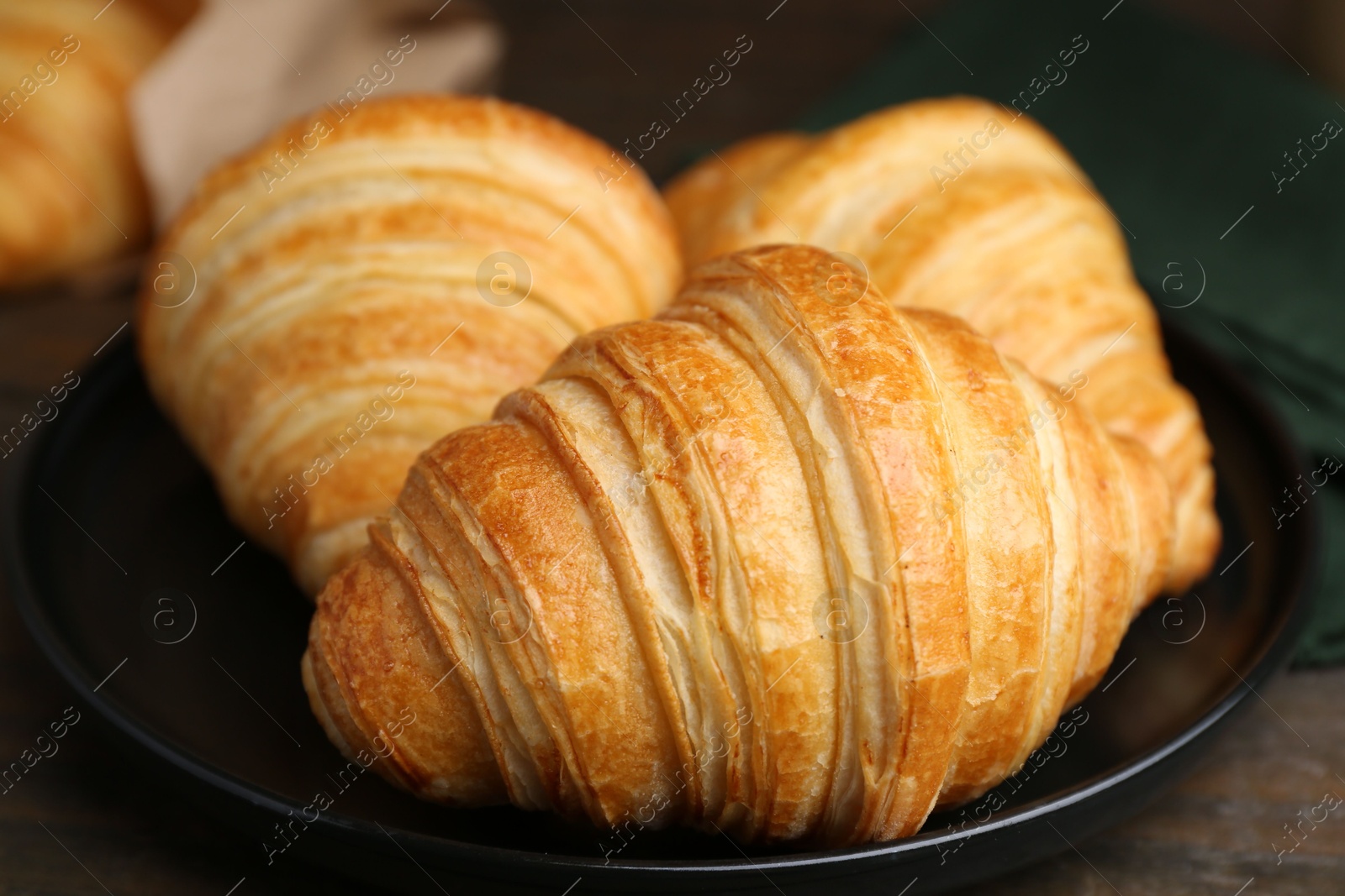 Photo of Tasty fresh croissants on wooden table, closeup. Puff pastry