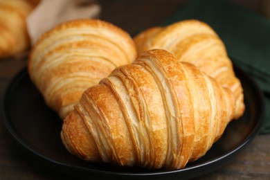 Photo of Tasty fresh croissants on wooden table, closeup. Puff pastry