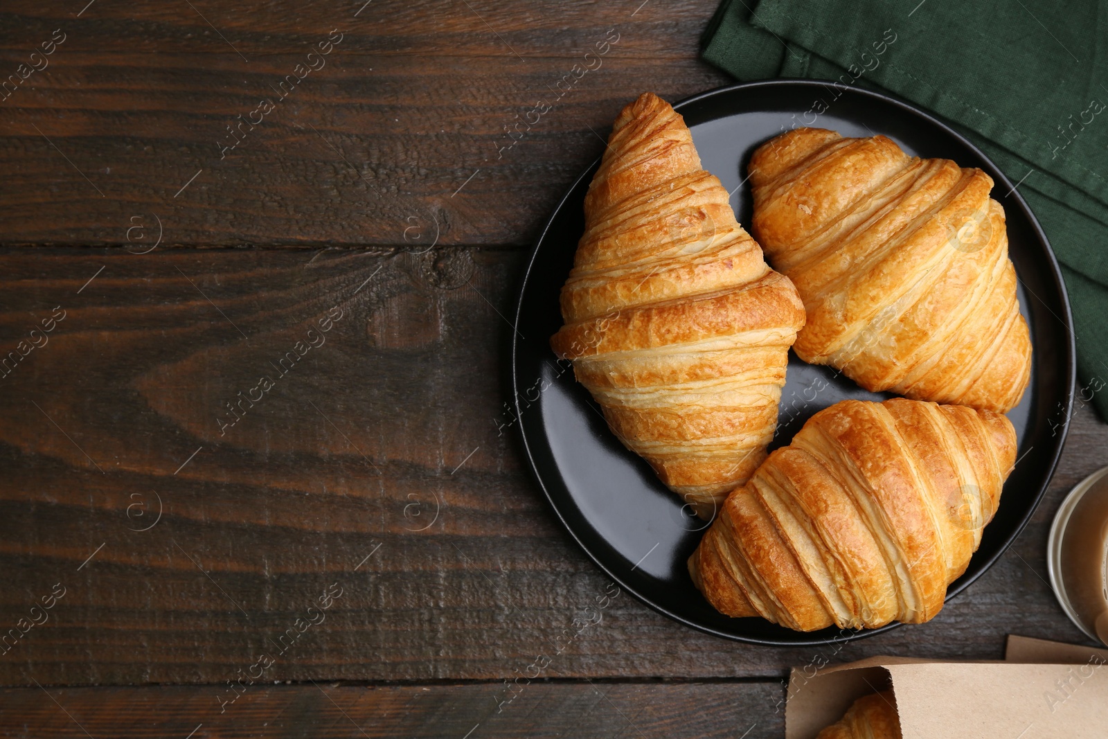 Photo of Tasty fresh croissants on wooden table, top view. Space for text