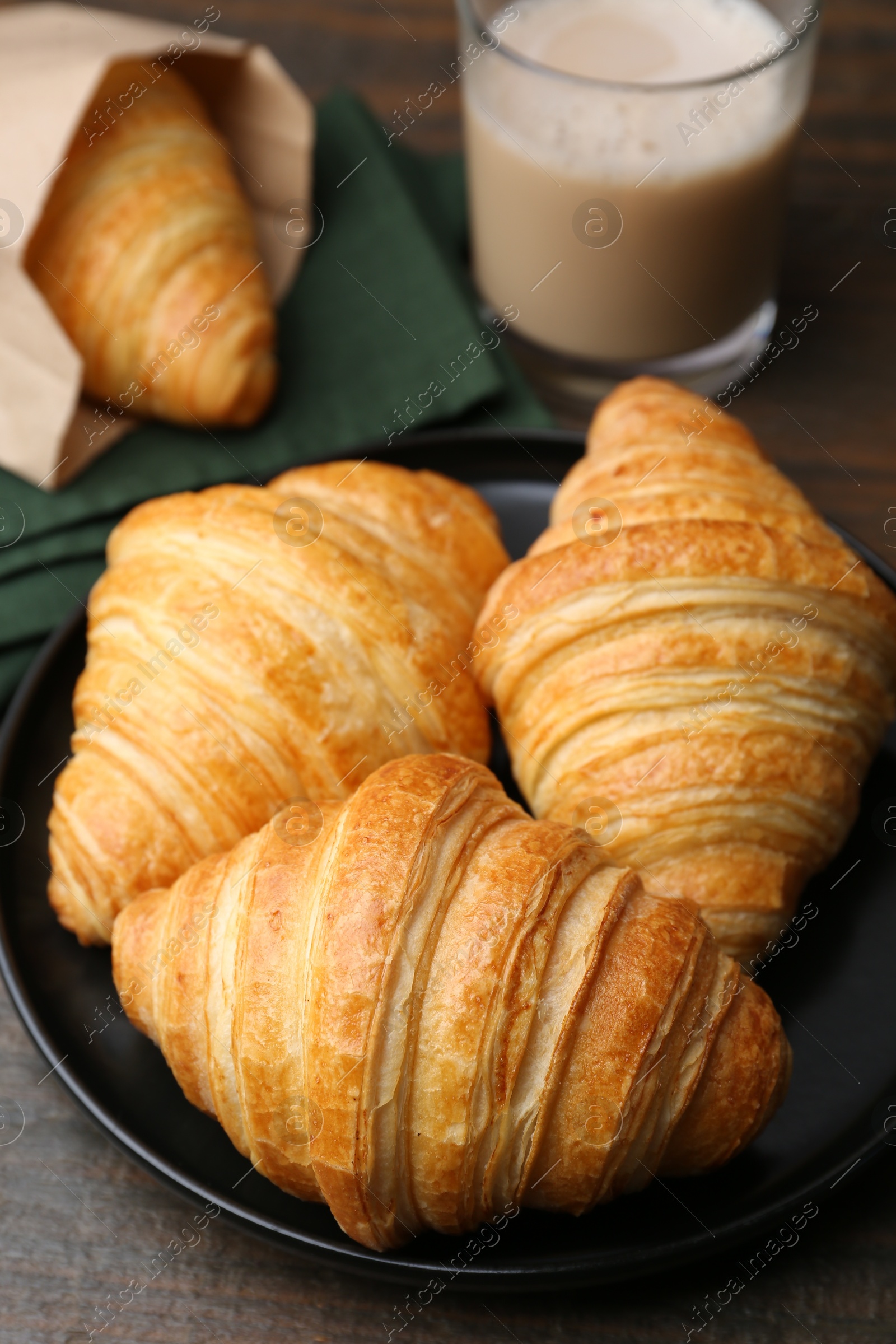 Photo of Tasty fresh croissants and drink on wooden table, closeup