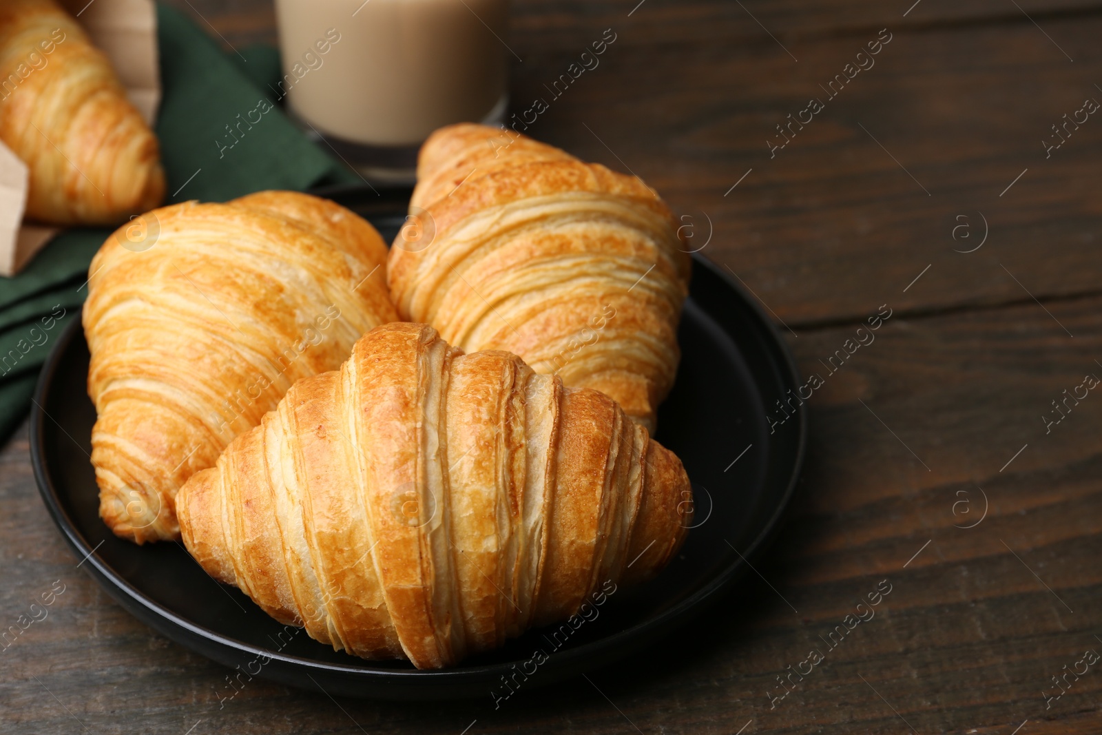 Photo of Tasty fresh croissants on wooden table, closeup. Space for text