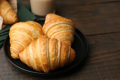 Photo of Tasty fresh croissants on wooden table, closeup. Space for text