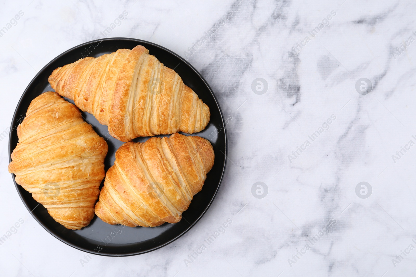 Photo of Tasty fresh croissants on white marble table, top view. Space for text