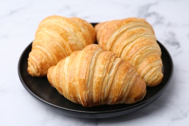 Photo of Tasty fresh croissants on white marble table, closeup. Puff pastry