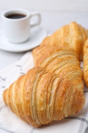 Photo of Tasty fresh croissants and cup of coffee on white marble table, closeup