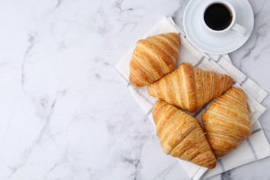 Photo of Tasty fresh croissants and cup of coffee on white marble table, flat lay. Space for text