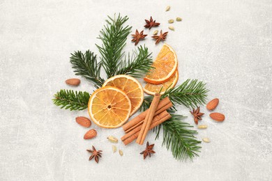 Photo of Different spices, dried orange slices and fir tree branches on light grey table, flat lay. Christmas season