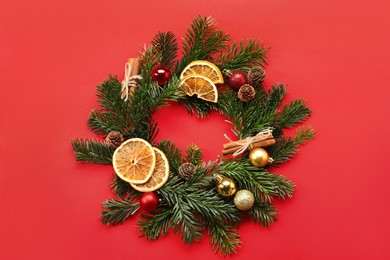 Photo of Different spices, dried orange slices and fir tree branches on red background, flat lay. Christmas season