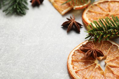 Photo of Different spices, dried orange slices and fir tree branches on light grey table, closeup with space for text. Christmas season