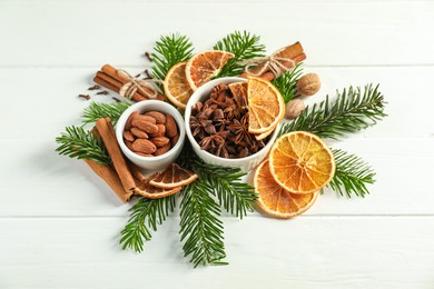 Photo of Different spices, dried orange slices and fir tree branches on white wooden table, above view. Christmas season