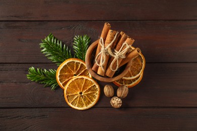 Photo of Different spices, dried orange slices and fir tree branches on wooden table, flat lay. Christmas season