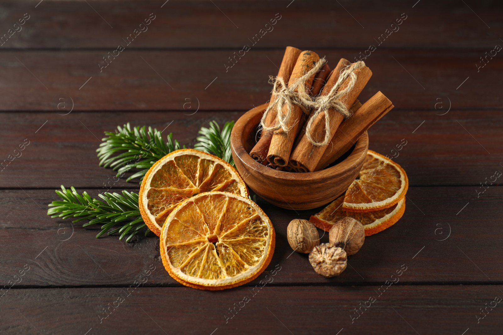 Photo of Different spices, dried orange slices and fir tree branches on wooden table. Christmas season