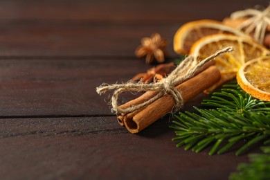 Photo of Different spices, dried orange slices and fir tree branches on wooden table, closeup with space for text. Christmas season