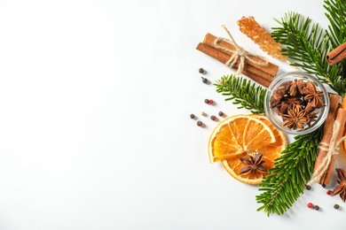 Photo of Different spices, dried orange slices and fir tree branches on white table, flat lay with space for text. Christmas season