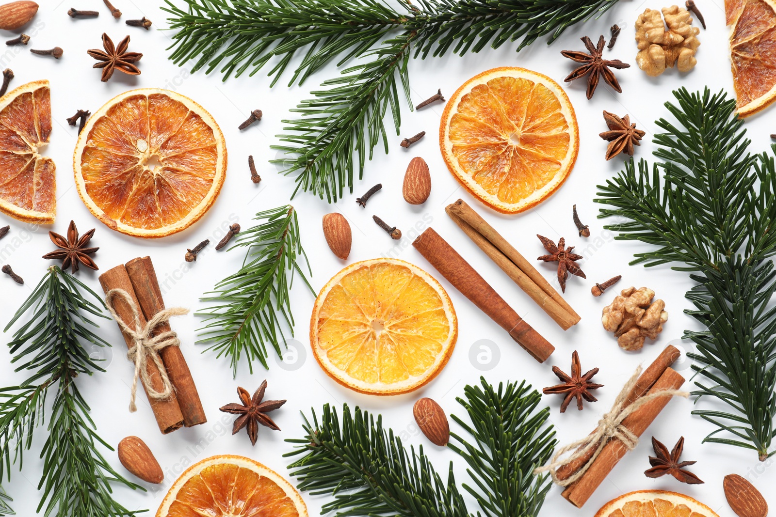 Photo of Different spices, dried orange slices and fir tree branches on white table, flat lay. Christmas season