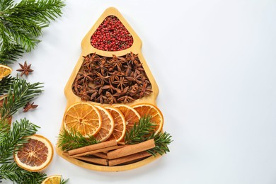 Photo of Different spices, dried orange slices and fir tree branches on white table, flat lay with space for text. Christmas season