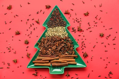 Photo of Different spices on red background, flat lay. Christmas season