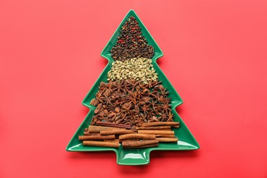 Photo of Different spices on red background, top view. Christmas season