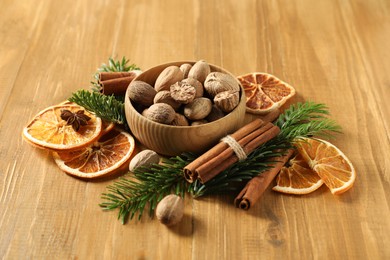 Photo of Different spices, dried orange slices and fir tree branches on wooden table. Christmas season