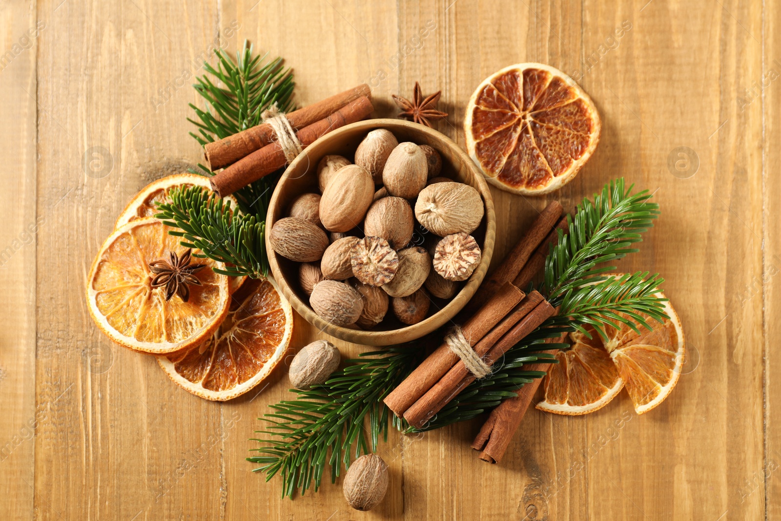 Photo of Different spices, dried orange slices and fir tree branches on wooden table, flat lay. Christmas season