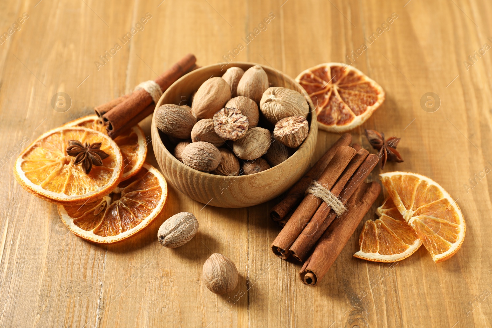 Photo of Different spices and dried orange slices on wooden table. Christmas season