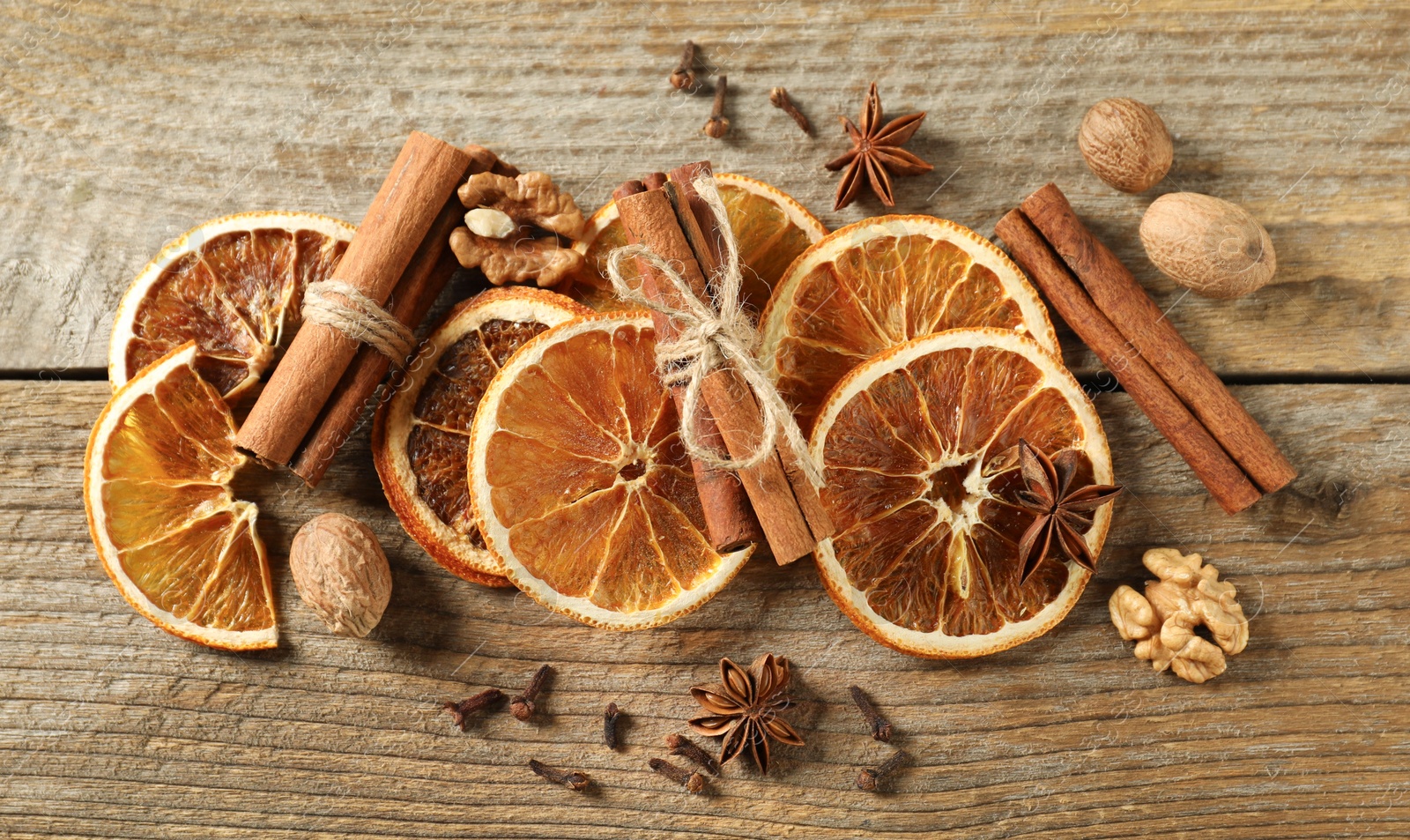 Photo of Different spices and dried orange slices on wooden table, flat lay. Christmas season