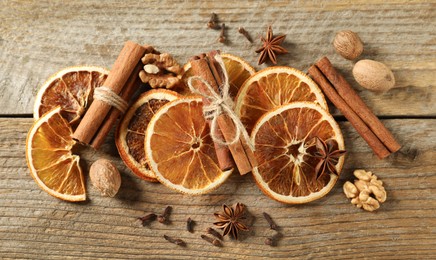 Photo of Different spices and dried orange slices on wooden table, flat lay. Christmas season