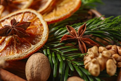 Photo of Different spices, dried orange slices and fir tree branches on table, closeup. Christmas season